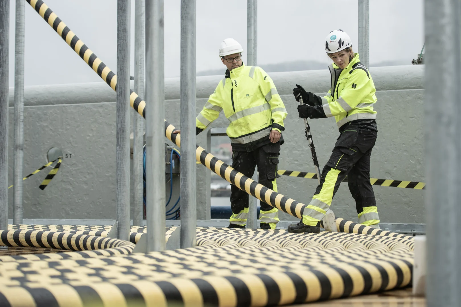 Two Vindra crew members guiding subsea cable across the deck