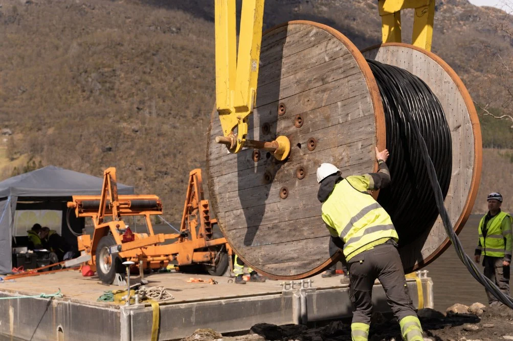 Crew in hi-vis handling a large cable drum on the modular barge