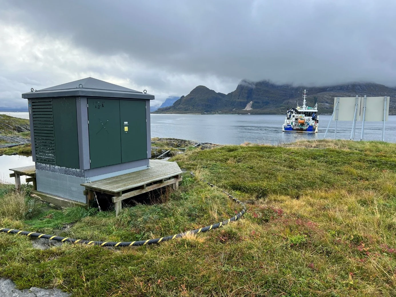 Substation kiosk on the island, cable running to the shore and the vessel beyond