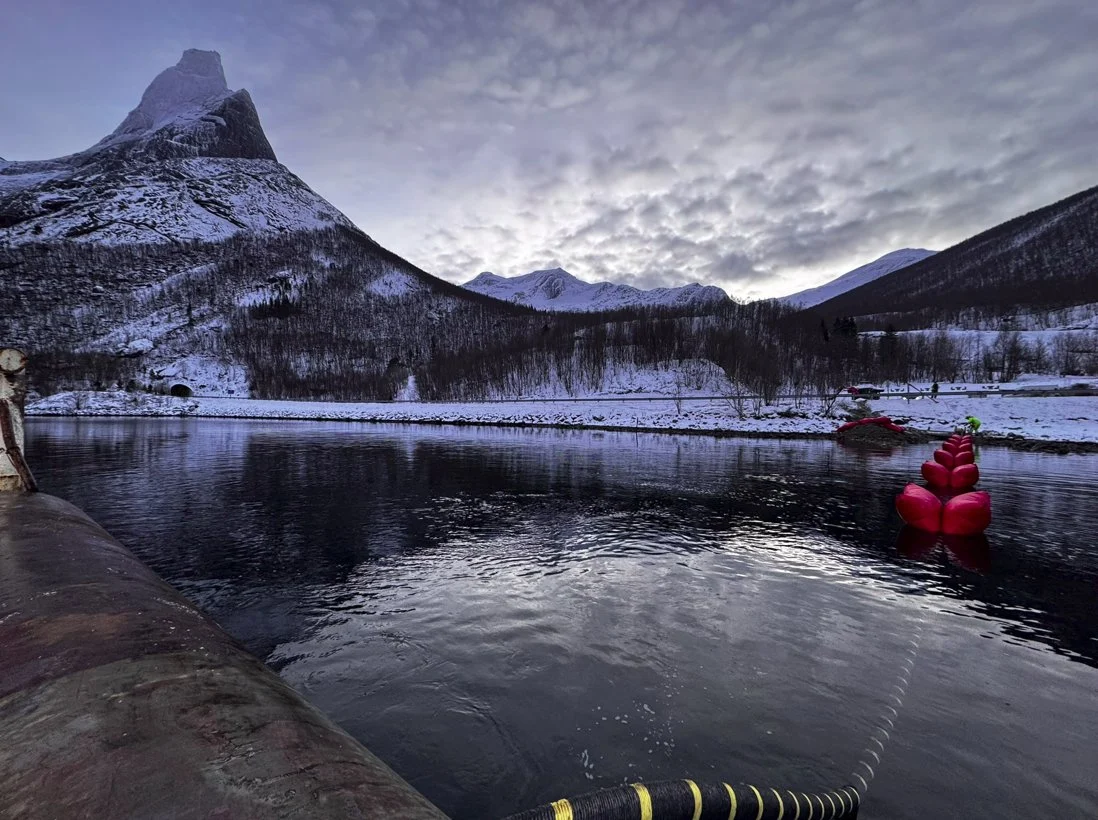 Cable landing at the shore with a red float in Stefjorden, snow-covered peaks behind