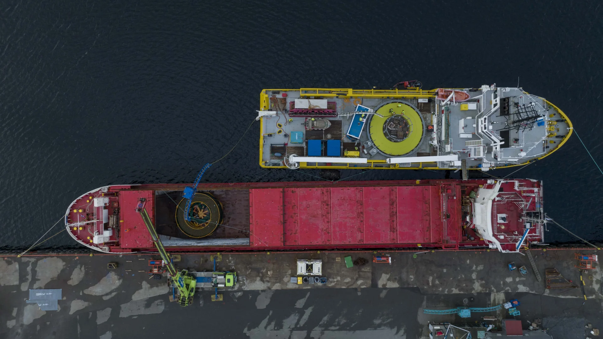 Cable vessel and transport barge loading alongside the quay, seen from above